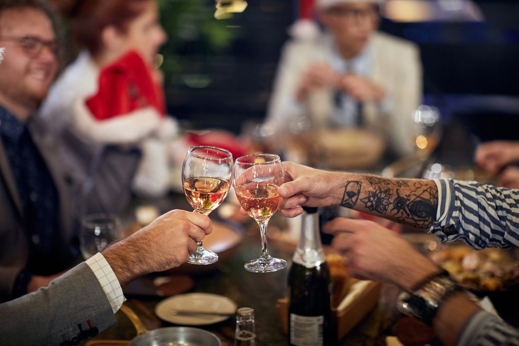 Gäste stoßen bei einer Weihnachtsfeier mit Wein an